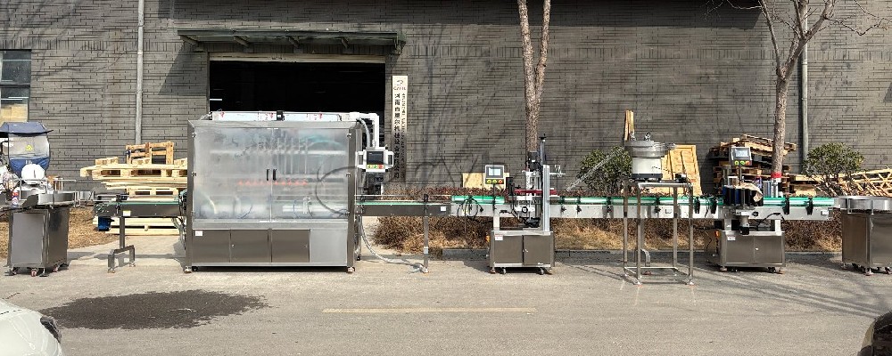 10-head servo-driven filling machine with enclosure, 4-wheel capping, star-wheel labeling, and bottle unscrambling/collection.